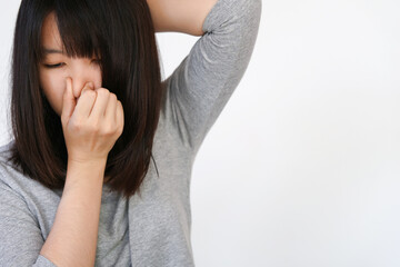 Asian woman raised her arms and made a bad expression while covering her nose because of the smell...