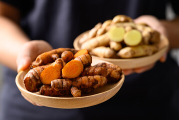 Fresh turmeric yelow and white in wooden bowl with hand, Spice in Asian cuisine