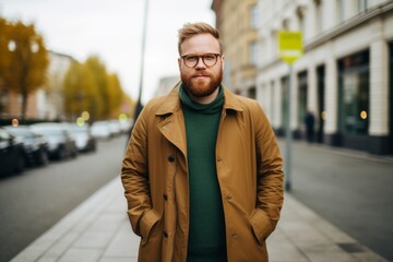 Portrait of a handsome young man in a coat and glasses in the city