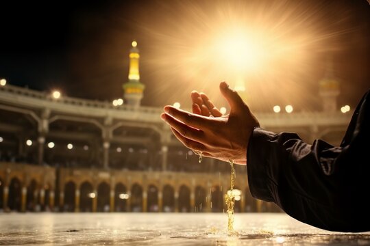 Men's hands praying in Mecca during the holy month of Ramadan with a crowd of people in the background.