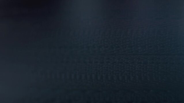 A macro close-up shot of a hard case zipper being opened, gold metal zip, black box, photography gear, cinematic lighting, static 4K video