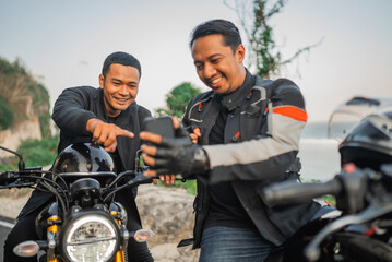 asiani rider holding phone and laughing about something on the phone with pointing gesture - obrazy, fototapety, plakaty
