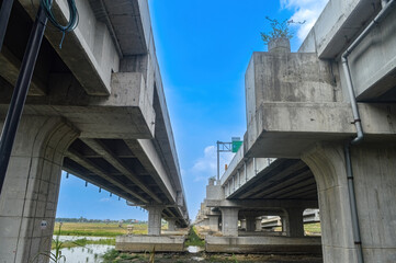 under a toll road bridge or highway with a bright blue sky.
