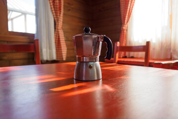 Coffee maker on red table at sunny morning.