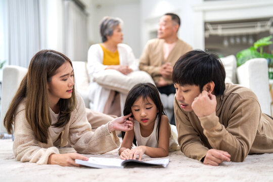 Portrait happy love asian family father and mother teach little daughter asian girl learn and study.Mom and asian young girl reading book making lessons in homeschool at home.Education