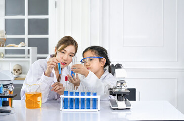 young attractive asian female scientist as a mentor is comparing tube lab experiment chemical  with...