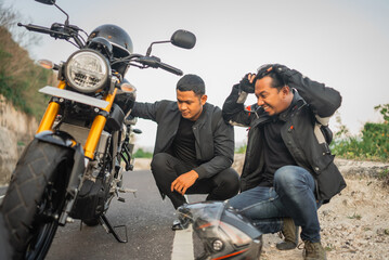 Fototapeta na wymiar indonesian rider feeling frustrated because his motorbike broken