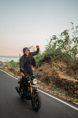 indonesian rider standing while riding motorbike with fist pump gesture