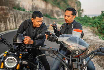 Fototapeta na wymiar asian male riders sitting on motorbike and conversating seriously while holding phone