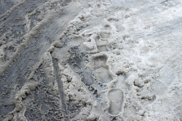 Car tire tracks, bicycle tire tracks, and footprints on slush ice on the streets in winter. Winter road safety concept.