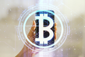 Double exposure of creative Bitcoin symbol and hand with cell phone on background. Cryptocurrency concept