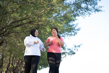 two asian women jogging together outdoors, healthy activity concept