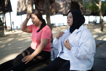 tired asian women sitting with wiping sweat gesture