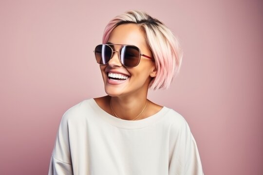 Portrait of beautiful young woman with pink hair and sunglasses over pink background