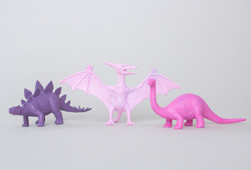 Tree small plastic dinosaur figurine on gray background, little plastic colorful statuettes © Dasha Lapshina