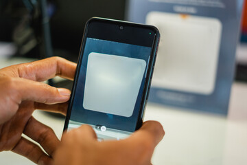 a person's hand using a mobile phone to scan a virtual barcode in a store