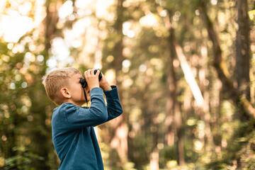 Child in the forest looking through binoculars exploring nature and wildlife	
