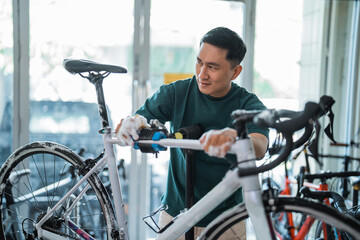 Asian young man washing bicycle with foaming soap at bike service station