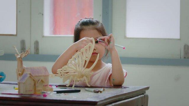 Asian girl is coloring on assembly wooden toy with magic color