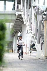 Confident businesswoman ride bicycle outside in downtown. Environmental conservation person commuting by cycling reduce carbon footprint. Bile to work, eco friendly alternative vehicle to green energy