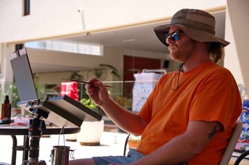 Young man with a hat painting in the backyard