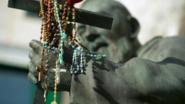 Statue of Saint Pio with rosaries draped over the Christian cross he holds in Atrani on the Italian Amalfi Coast.