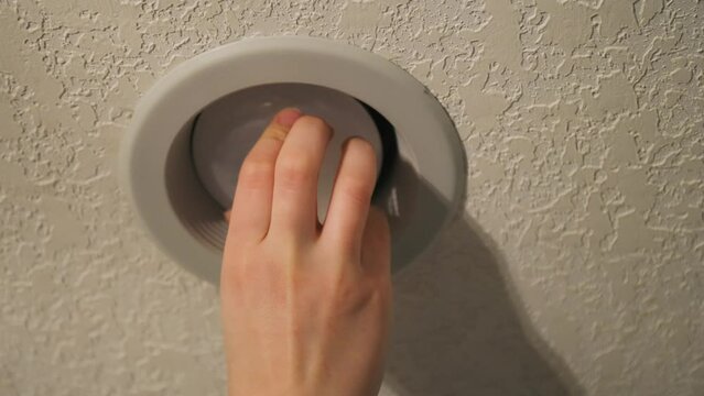 A close up of a person installing a lightbulb 