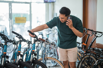 young man on phone while checking hangrip standing in bike shop