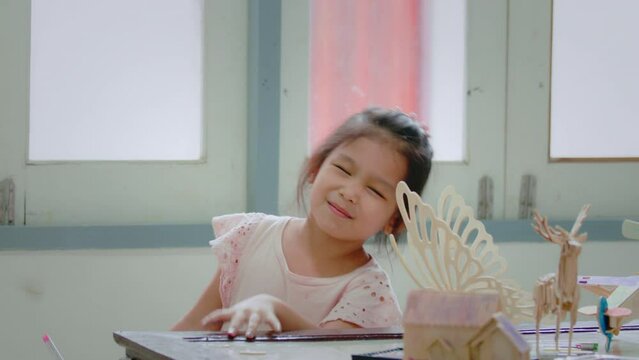 Asian girl is coloring on assembly wooden toy with magic color