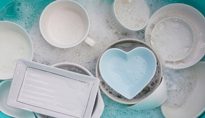 Plates and bowl soaking in foam of dishwashing liquid