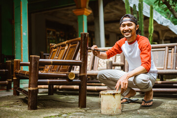 a craftsman using brushes and lacquers when finishing bamboo chair crafts outside the house