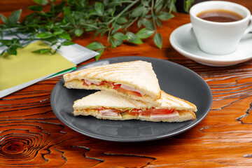 Sandwich with ham, cheese and tomato. Breakfast. On a wooden table.