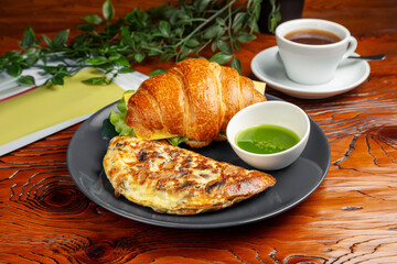 Egg omelette, croissant with cheese. Breakfast. On a wooden table.