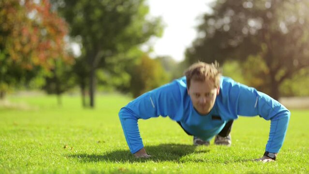 Man, push up and fitness face in a park for workout, exercise and strength training on field grass. Sport, athlete and morning with a male person in nature on a lawn with health and wellness routine