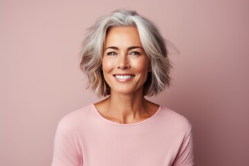 Portrait of a smiling middle-aged woman with short grey hair on a pink background