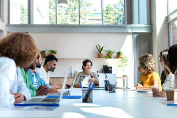 Multiracial coworkers share ideas in business meeting in bright spacious office. Copy space....