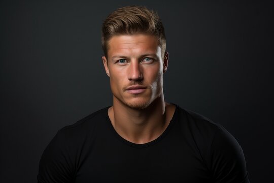 Portrait of a handsome young man in black t-shirt on dark background