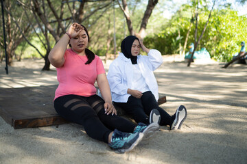 sporty asian women sitting with wiping sweat gesture