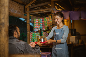 female waitress wearing an apron serves food and drinks to customers at a traditional stall