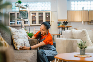 female shop assistant working while squatting to tidy up a sofa at a furniture store