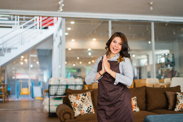 woman attracts shop assistant with welcome hand gesture standing in furniture store