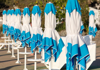 Closed umbrellas near the sun loungers on the beach