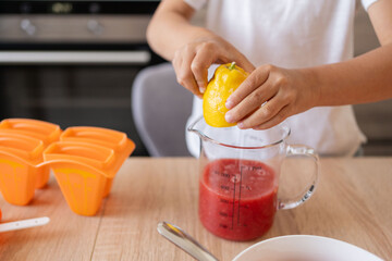 Child girl cooking berry popsicles at home
