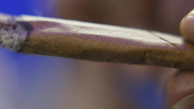 panning shot of a black man holding a burning blunt or marijuana cigarette