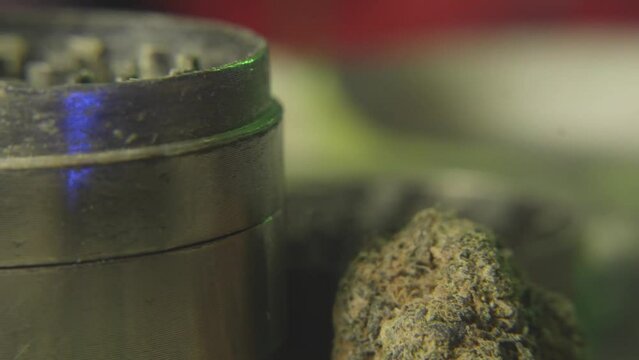 panning shot from a cannabis or marijuana bud to a weed grinder used for making the reefer fine enough to roll into a joint
