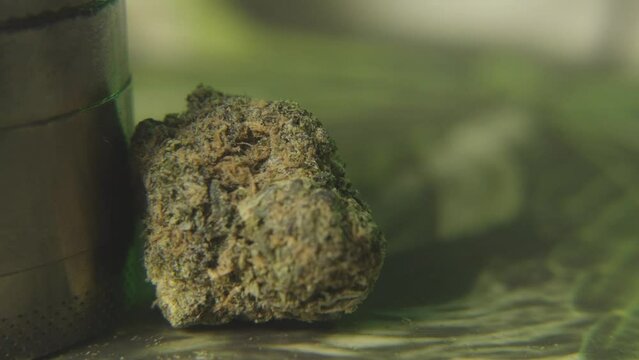 a panning shot to a close up  bud of marijuana and a weed grinder