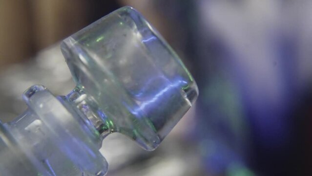 a man reaches into a bag of marijuana behind a glass smoking utensil