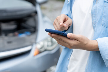breakdown, broken car, repair. Woman uses mobile phone check insurance premiums through application...