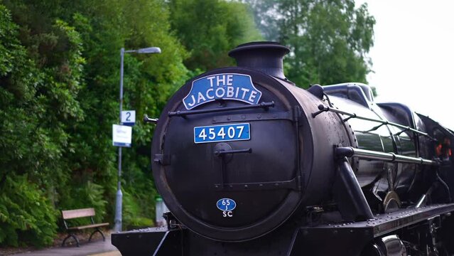 Jacobite train, steam locomotive for tourist, coming from Glenfinnan viaduct bridge in Scotland. Jacobite Railway scenic tourism attraction in Britain. 