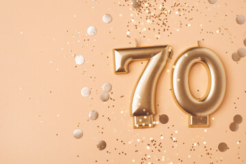 70 years celebration. Greeting banner. Gold candles in the form of number seventy on peach...